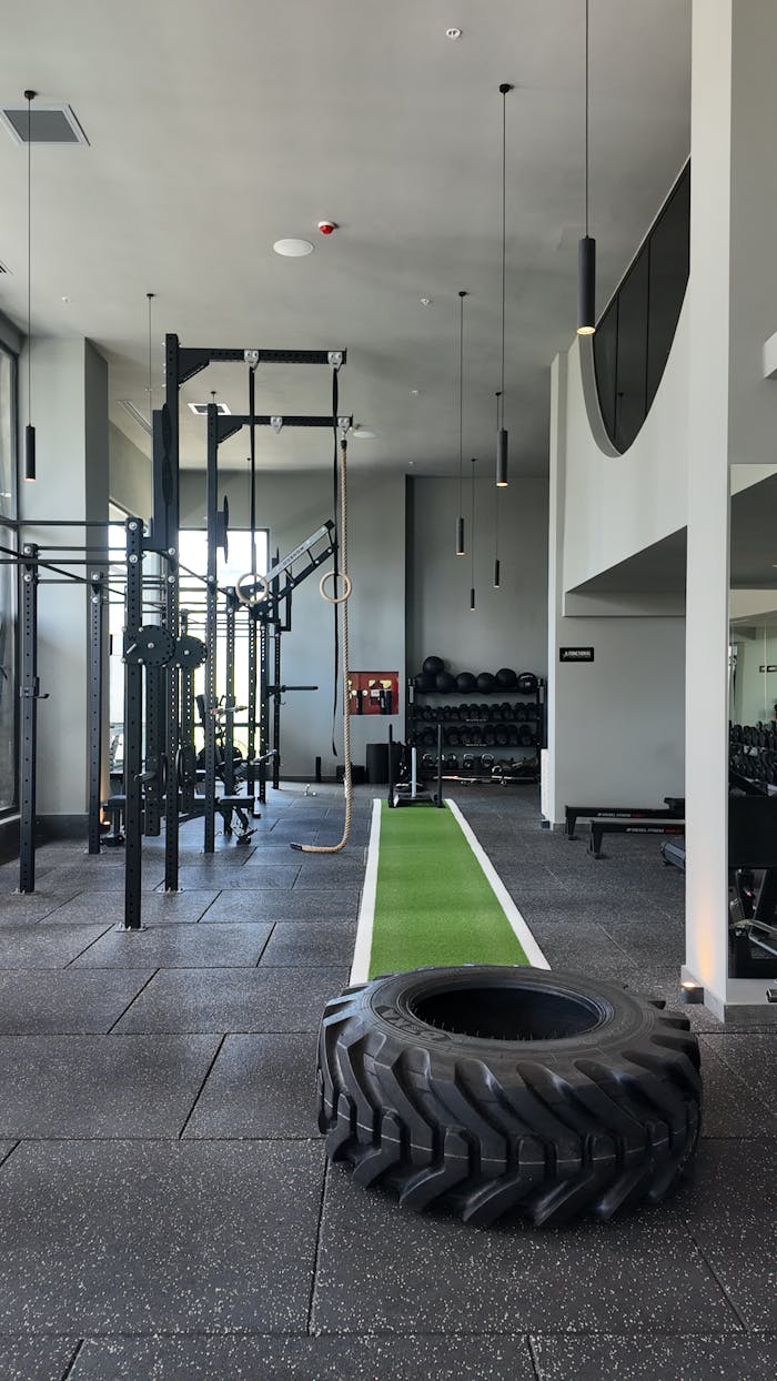 services-04 Spacious gym filled with modern exercise machines and a green training track.